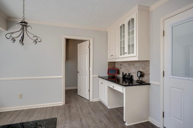 kitchen featuring dark countertops, white cabinetry, glass insert cabinets, and wood finished floors