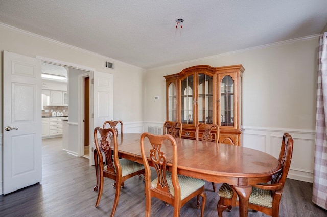 dining room with wainscoting, visible vents, crown molding, and wood finished floors