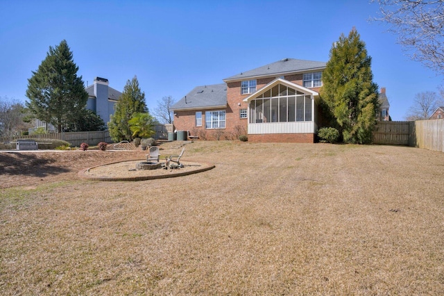 back of property with a lawn, an outdoor fire pit, a sunroom, cooling unit, and a fenced backyard