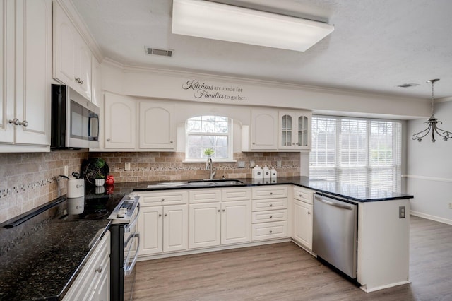 kitchen with visible vents, light wood-style flooring, appliances with stainless steel finishes, a peninsula, and a sink