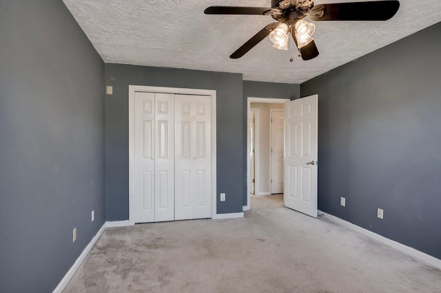 unfurnished bedroom with carpet floors, a textured ceiling, baseboards, and a closet