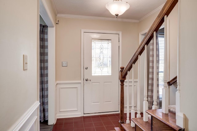 foyer entrance featuring crown molding, a wainscoted wall, and plenty of natural light