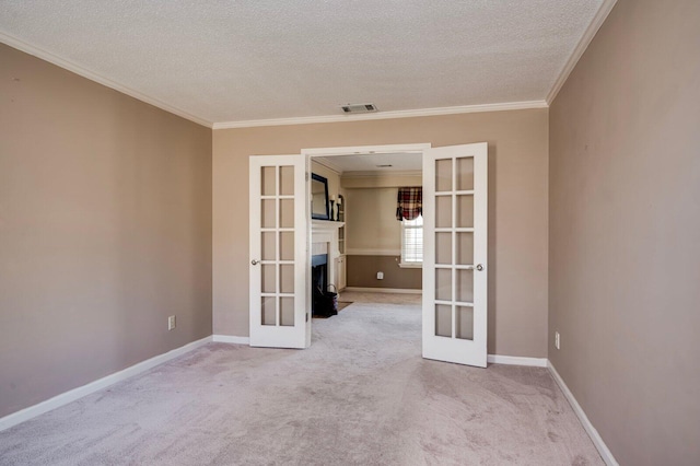 spare room featuring french doors, crown molding, visible vents, light carpet, and baseboards