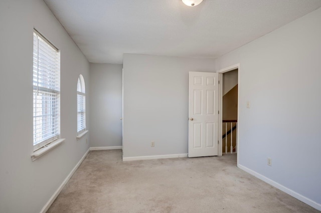 carpeted spare room featuring a textured ceiling and baseboards