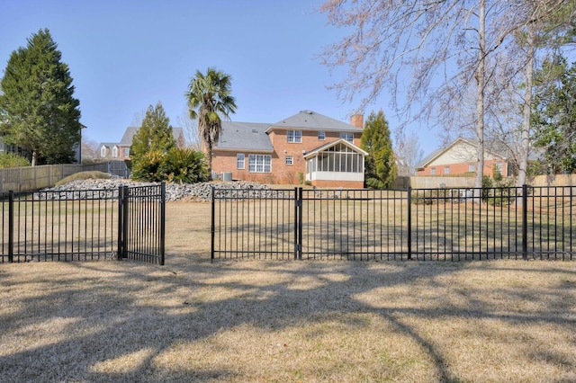 view of front facade featuring a sunroom, a gate, fence, and a front yard