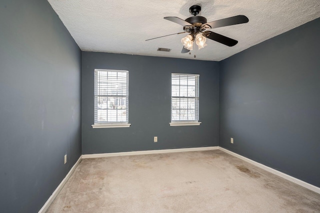 unfurnished room with a textured ceiling, carpet floors, visible vents, and baseboards