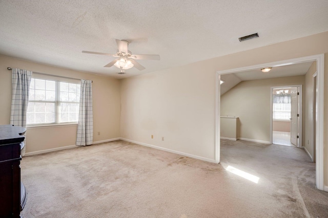 carpeted empty room with a ceiling fan, a textured ceiling, visible vents, and a wealth of natural light