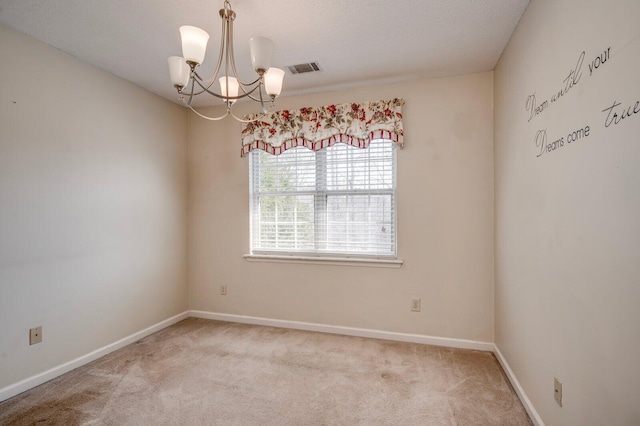 spare room with baseboards, carpet, visible vents, and a notable chandelier