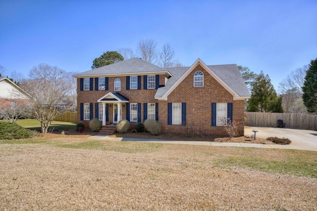 view of front of house featuring brick siding, a front yard, and fence