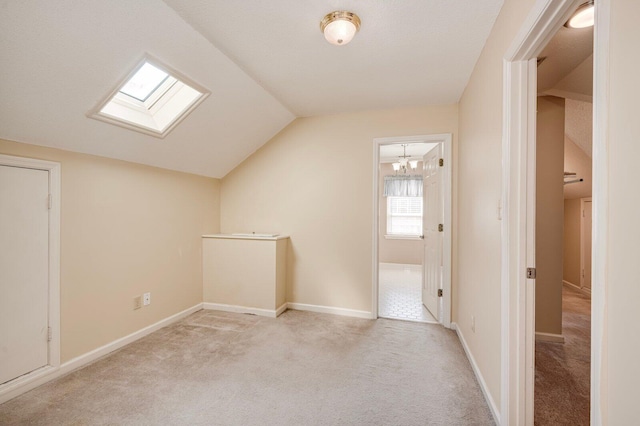 additional living space with light carpet, lofted ceiling with skylight, and baseboards