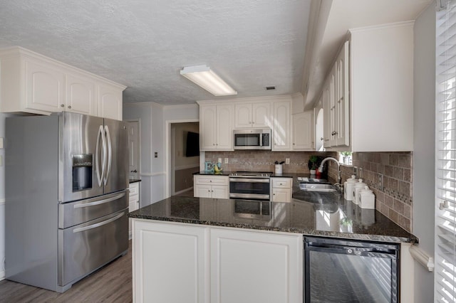 kitchen featuring stainless steel appliances, a sink, a peninsula, and decorative backsplash