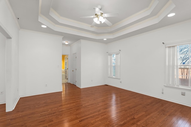 unfurnished room featuring hardwood / wood-style flooring, plenty of natural light, a raised ceiling, and ceiling fan