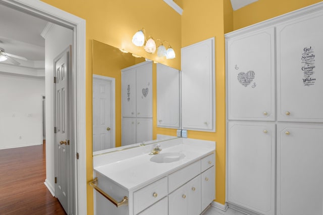 bathroom with crown molding, ceiling fan, vanity, and hardwood / wood-style floors