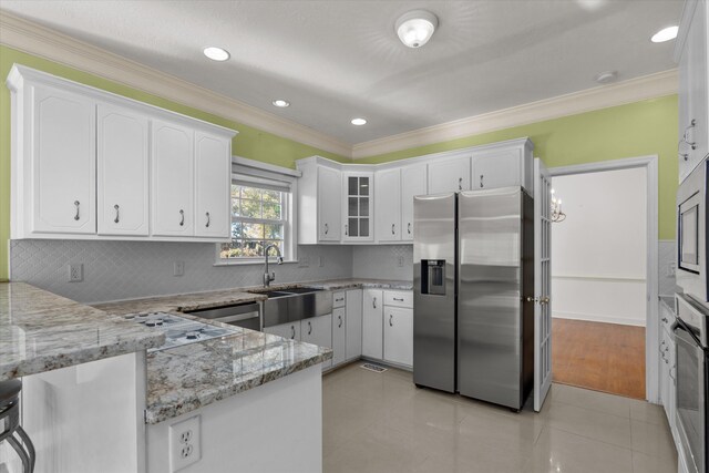 kitchen with sink, appliances with stainless steel finishes, light stone counters, white cabinets, and kitchen peninsula