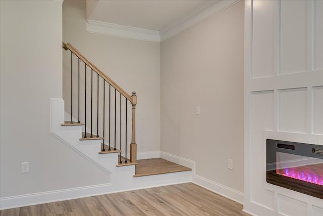 staircase featuring baseboards, ornamental molding, and wood finished floors