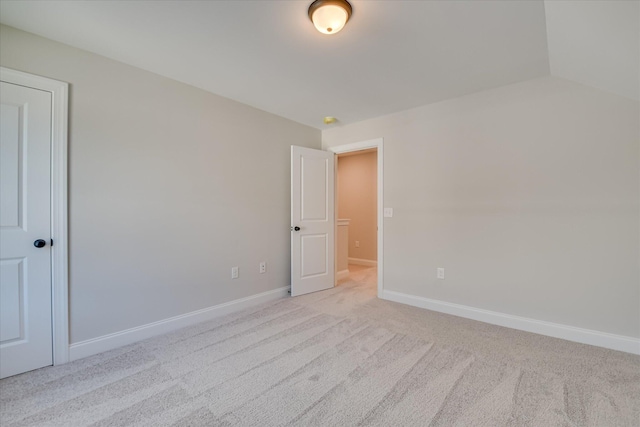 spare room featuring light colored carpet and baseboards