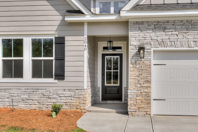 doorway to property with stone siding and a garage