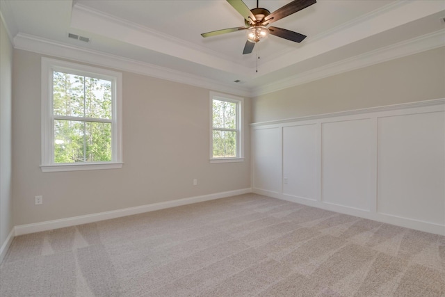 empty room with crown molding, a decorative wall, a tray ceiling, and visible vents