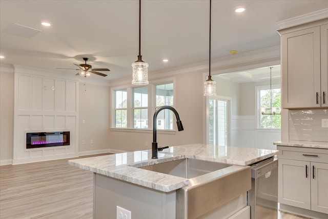 kitchen featuring crown molding, light stone counters, a sink, dishwasher, and pendant lighting