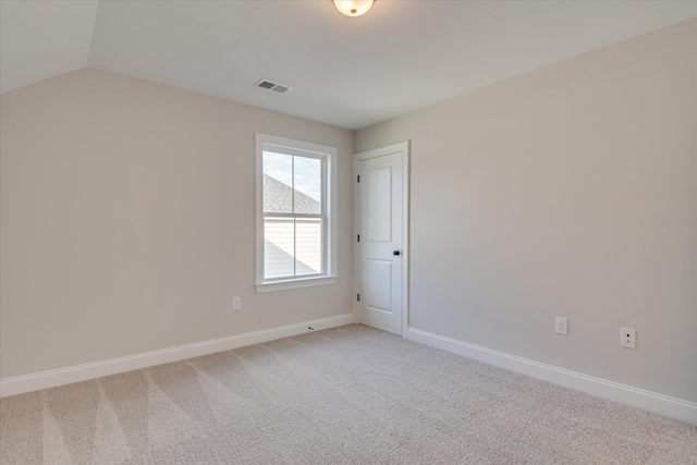 unfurnished room with baseboards, visible vents, light carpet, and vaulted ceiling