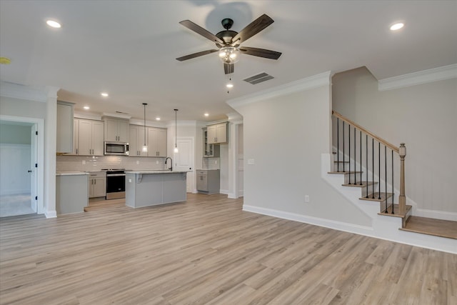 kitchen featuring crown molding, stainless steel appliances, open floor plan, gray cabinetry, and visible vents