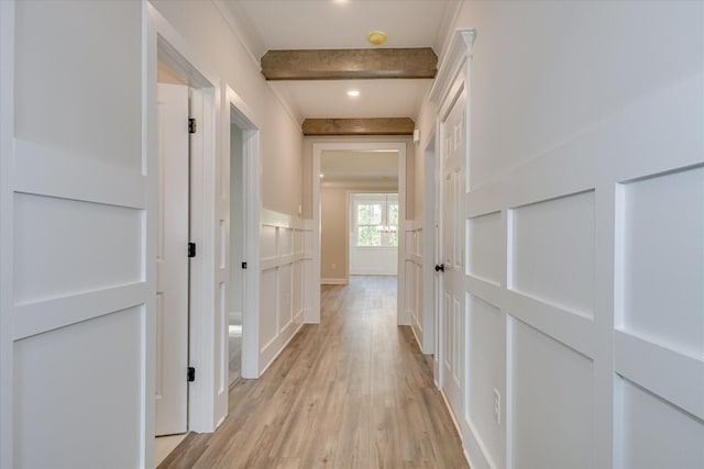 corridor featuring light wood finished floors, a decorative wall, and wainscoting