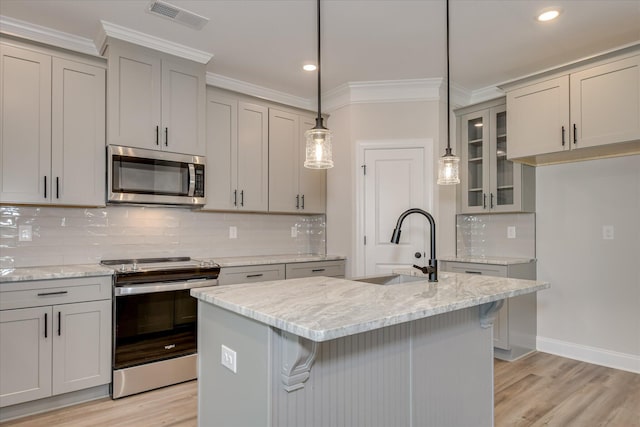 kitchen featuring appliances with stainless steel finishes, a sink, visible vents, gray cabinetry, and ornamental molding