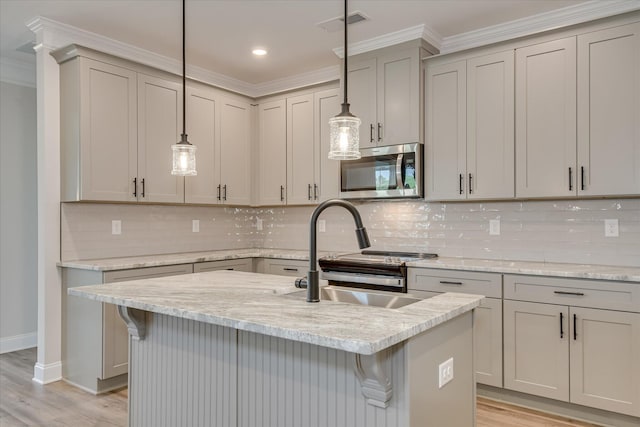 kitchen with ornamental molding, stainless steel microwave, a sink, light wood finished floors, and gray cabinetry