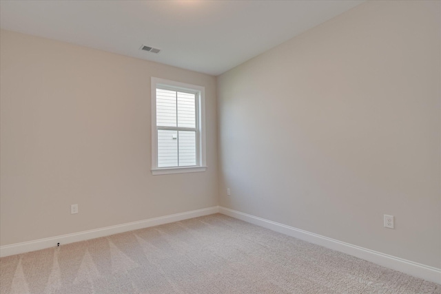 spare room featuring light colored carpet, baseboards, and visible vents