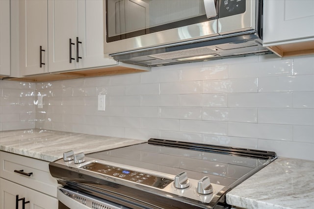 kitchen with decorative backsplash, white cabinets, light stone countertops, and stainless steel appliances