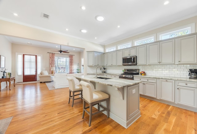 kitchen with tasteful backsplash, visible vents, a kitchen bar, appliances with stainless steel finishes, and a sink