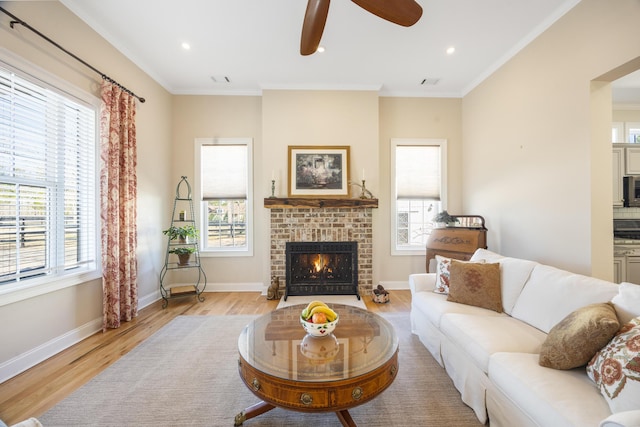 living area featuring light wood-style flooring, a fireplace, baseboards, and ornamental molding