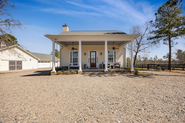 bungalow-style house with ceiling fan, fence, covered porch, a chimney, and an outbuilding