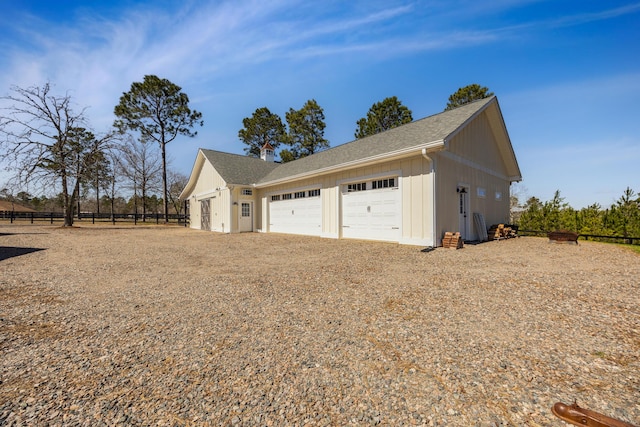 exterior space with fence, an outdoor structure, a garage, dirt driveway, and board and batten siding