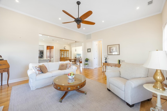 living room with light wood-type flooring, visible vents, and crown molding