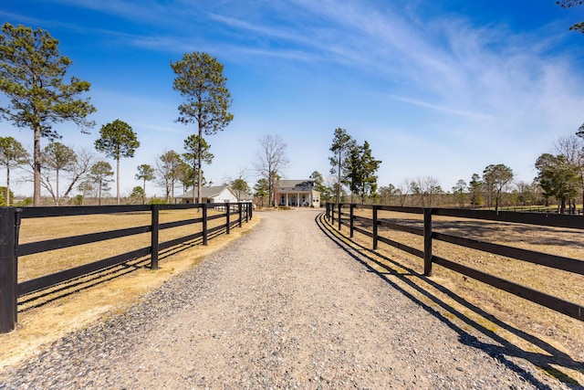 view of road with a rural view and gravel driveway