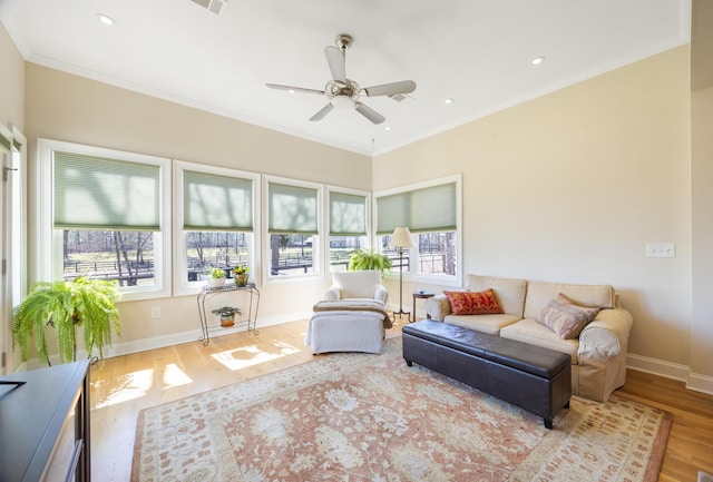 living area featuring wood finished floors, baseboards, a wealth of natural light, and ornamental molding