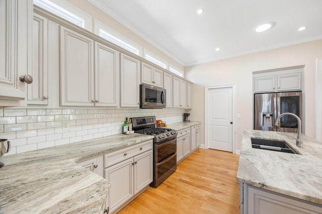 kitchen with light wood finished floors, a sink, decorative backsplash, stainless steel appliances, and crown molding