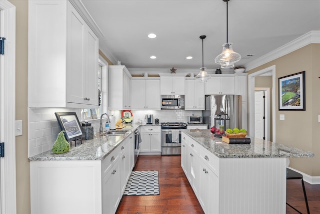 kitchen featuring sink, a center island, hanging light fixtures, appliances with stainless steel finishes, and white cabinets