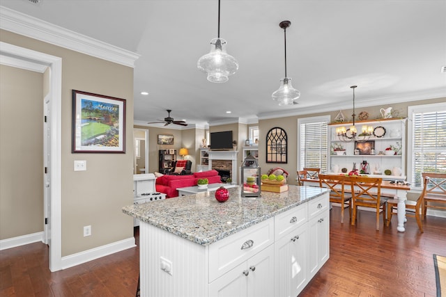 kitchen featuring decorative light fixtures, a center island, ornamental molding, ceiling fan with notable chandelier, and white cabinets