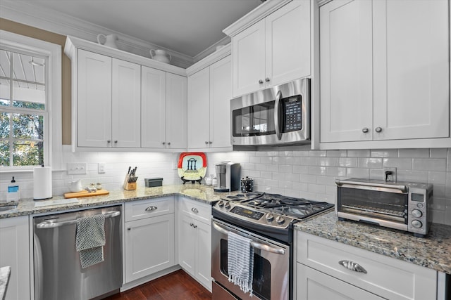 kitchen featuring ornamental molding, appliances with stainless steel finishes, decorative backsplash, and white cabinets