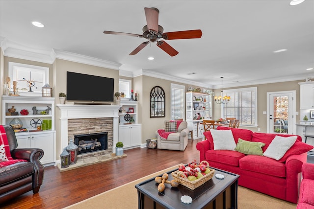 living room with ceiling fan with notable chandelier, a fireplace, ornamental molding, and dark hardwood / wood-style floors