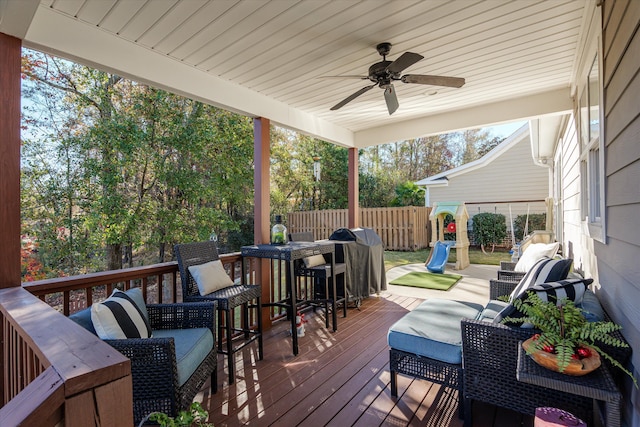 wooden deck with a playground and ceiling fan