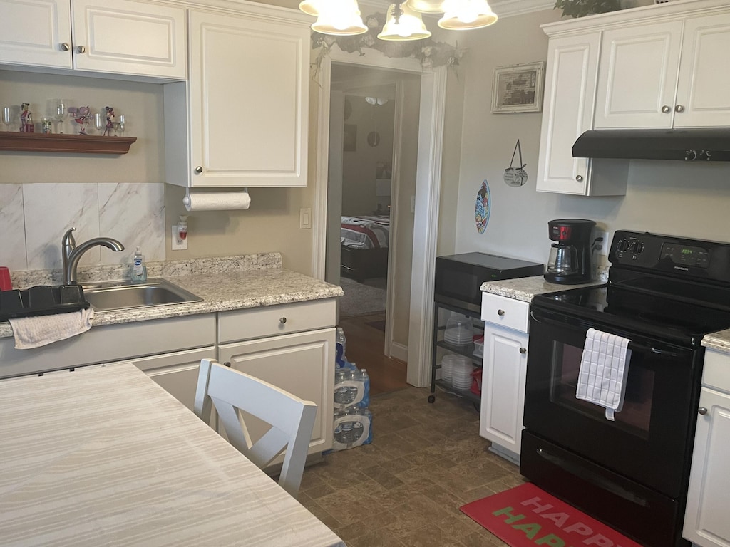 kitchen with black electric range oven, an inviting chandelier, white cabinets, crown molding, and sink