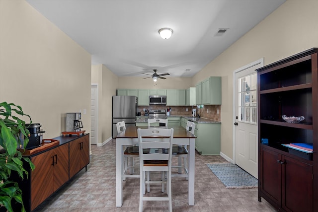 kitchen with decorative backsplash, ceiling fan, visible vents, green cabinets, and stainless steel appliances