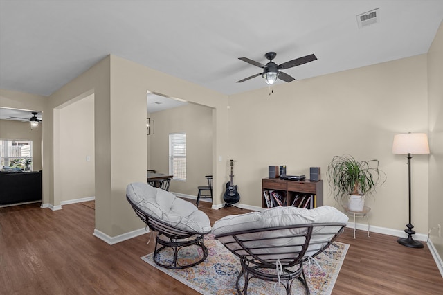 living area featuring a ceiling fan, visible vents, a wealth of natural light, and wood finished floors