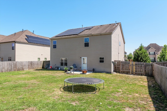 back of property featuring a fenced backyard, a trampoline, and a lawn