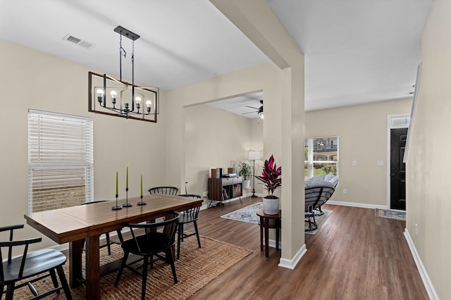 dining room with baseboards, visible vents, wood finished floors, and ceiling fan with notable chandelier