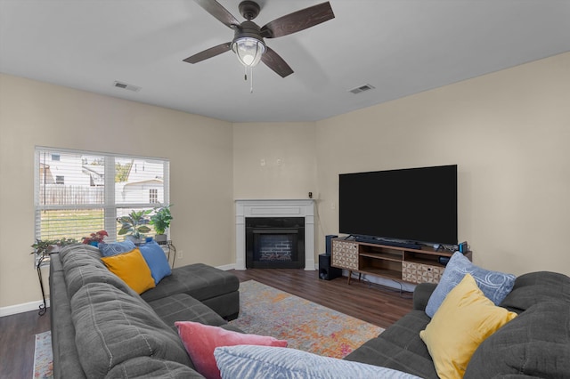 living area featuring ceiling fan, visible vents, a fireplace, wood finished floors, and baseboards