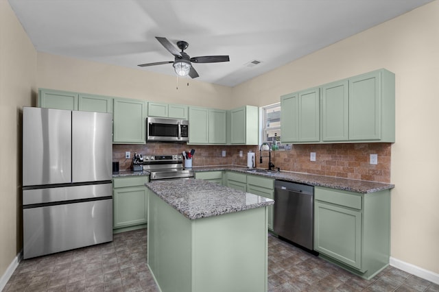kitchen with a sink, green cabinetry, appliances with stainless steel finishes, and backsplash